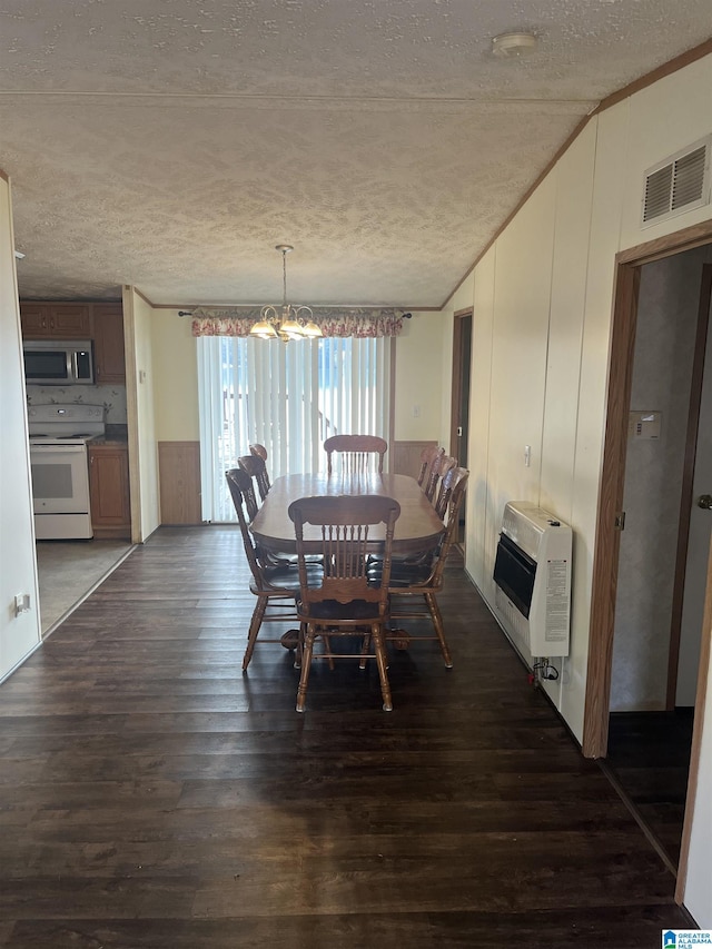 dining area with dark hardwood / wood-style flooring, a chandelier, heating unit, and a textured ceiling