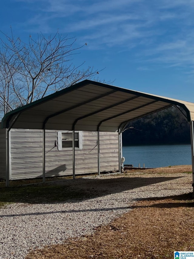 view of vehicle parking with a carport and a water view