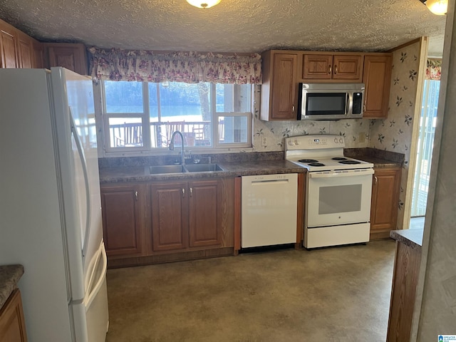 kitchen with white appliances, concrete flooring, sink, and a textured ceiling