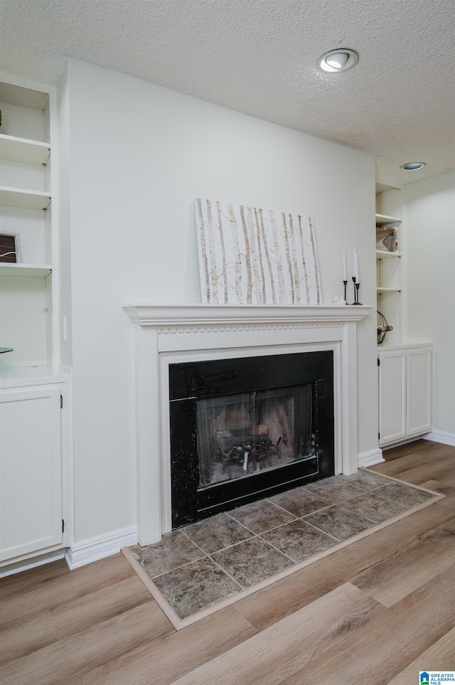 room details with hardwood / wood-style flooring, built in features, and a textured ceiling