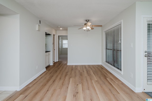 spare room with ceiling fan, a textured ceiling, and light hardwood / wood-style floors