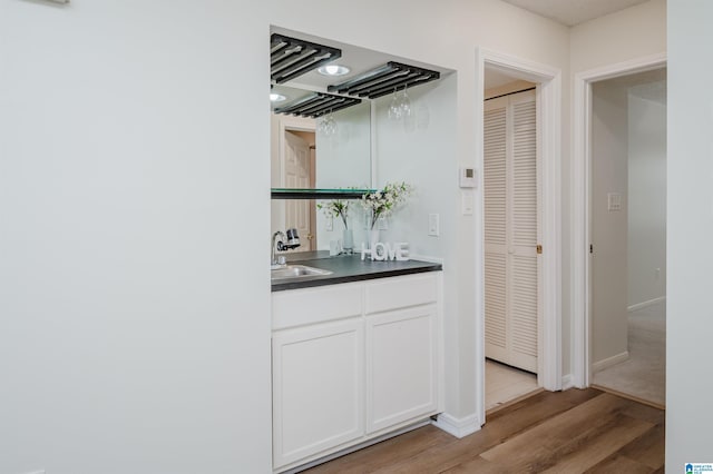 bar with sink, white cabinets, and light hardwood / wood-style flooring