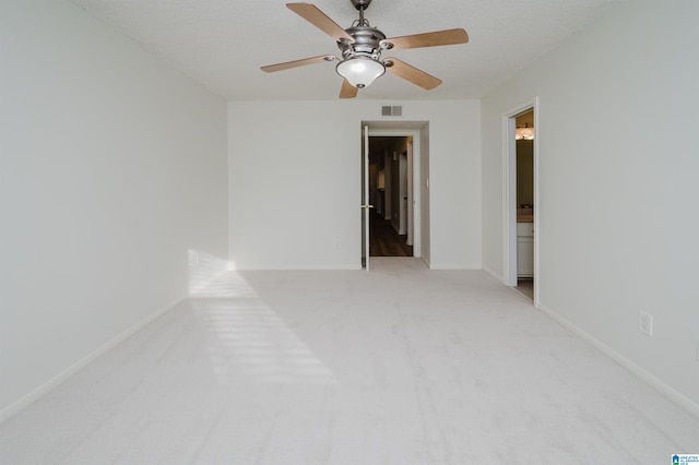 unfurnished room with light carpet, ceiling fan, and a textured ceiling