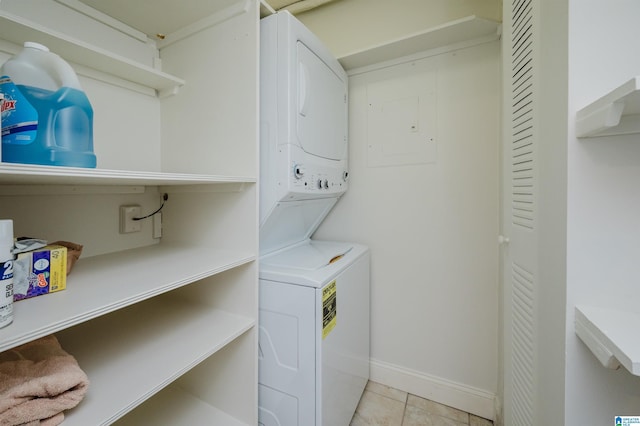 laundry area with stacked washer / drying machine, electric panel, and light tile patterned flooring