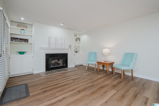 living area with built in shelves and light wood-type flooring