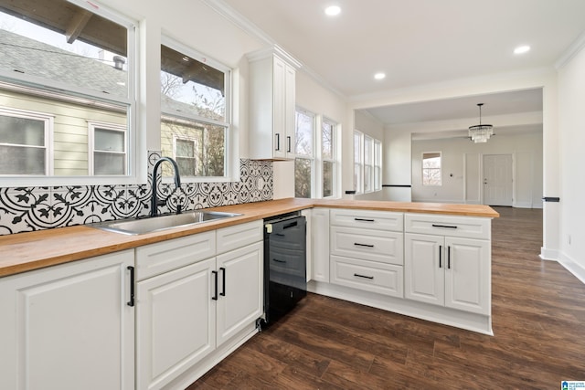 kitchen featuring pendant lighting, sink, black dishwasher, white cabinets, and wood counters