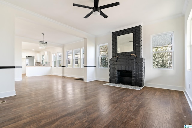 unfurnished living room featuring crown molding, dark wood-type flooring, a brick fireplace, and a wealth of natural light