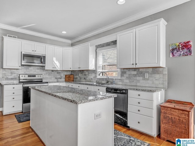 kitchen featuring stainless steel appliances, light hardwood / wood-style floors, white cabinets, and a kitchen island