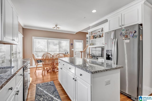 kitchen with dishwashing machine, white cabinetry, a kitchen island, stainless steel fridge with ice dispenser, and dark stone counters