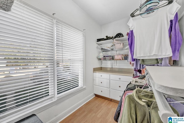 walk in closet with light hardwood / wood-style floors