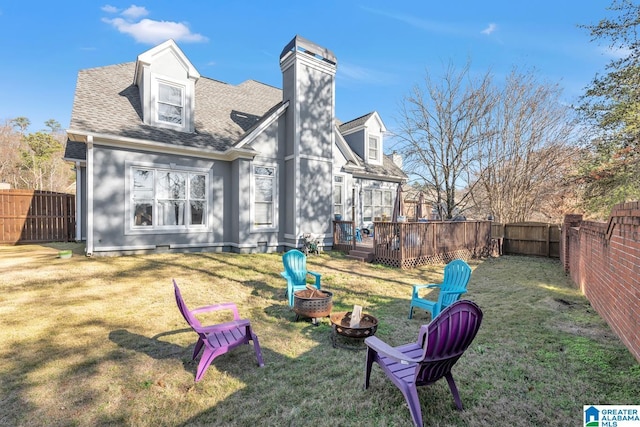 back of property featuring a yard, a fire pit, and a deck