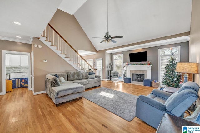 living room featuring ornamental molding, high vaulted ceiling, light hardwood / wood-style flooring, and a wealth of natural light