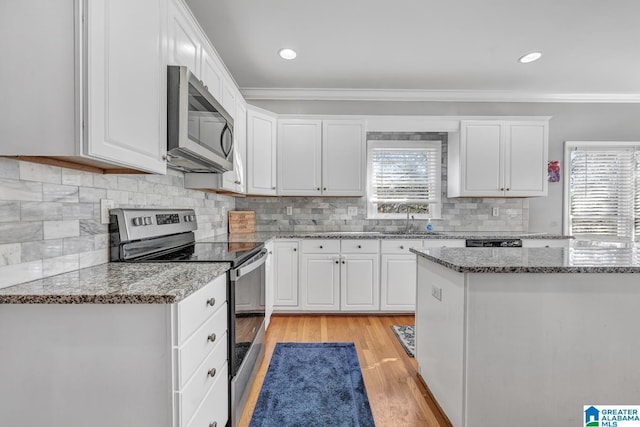 kitchen with stone counters, appliances with stainless steel finishes, sink, and white cabinets