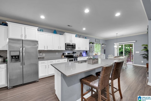 kitchen featuring pendant lighting, sink, stainless steel appliances, an island with sink, and white cabinets