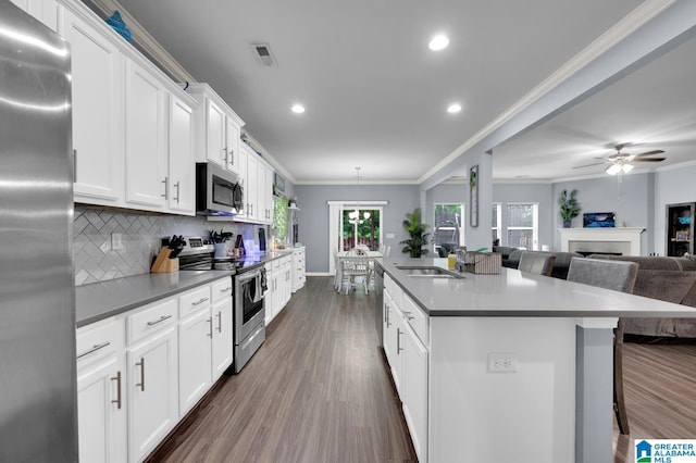 kitchen with appliances with stainless steel finishes, sink, white cabinets, and a kitchen bar