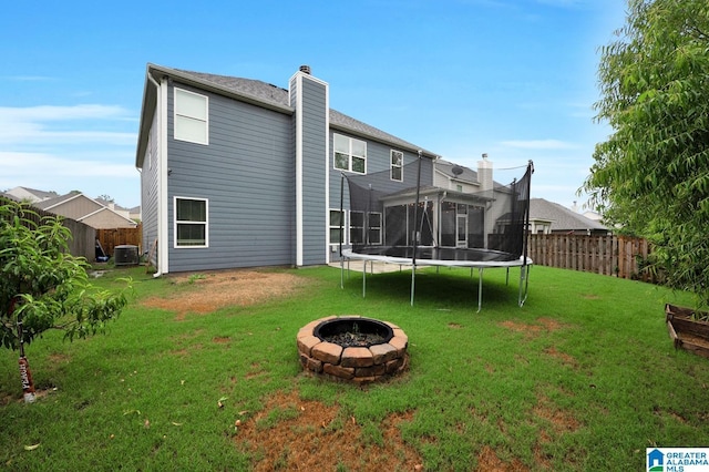 rear view of house featuring cooling unit, a lawn, and an outdoor fire pit