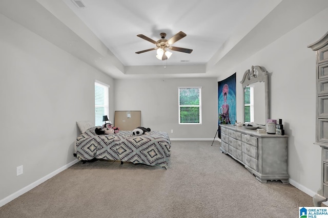 carpeted bedroom with a tray ceiling and ceiling fan