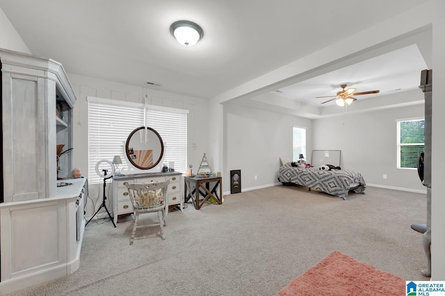 bedroom with ceiling fan, multiple windows, a raised ceiling, and light carpet