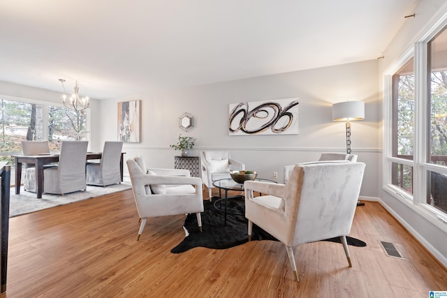 living room featuring a healthy amount of sunlight, a notable chandelier, and light hardwood / wood-style floors