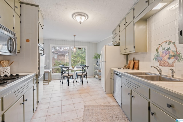 kitchen featuring light tile patterned flooring, sink, appliances with stainless steel finishes, pendant lighting, and decorative backsplash