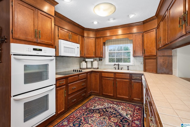 kitchen with sink, white appliances, tile countertops, and backsplash