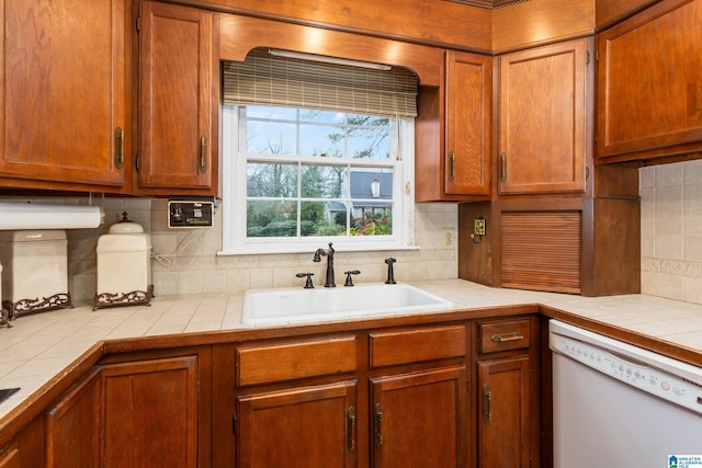 kitchen with sink, tile counters, white dishwasher, and decorative backsplash