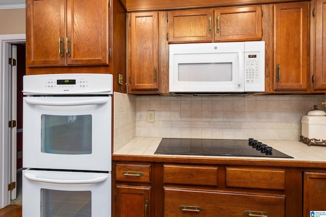 kitchen with tile counters, white appliances, and decorative backsplash