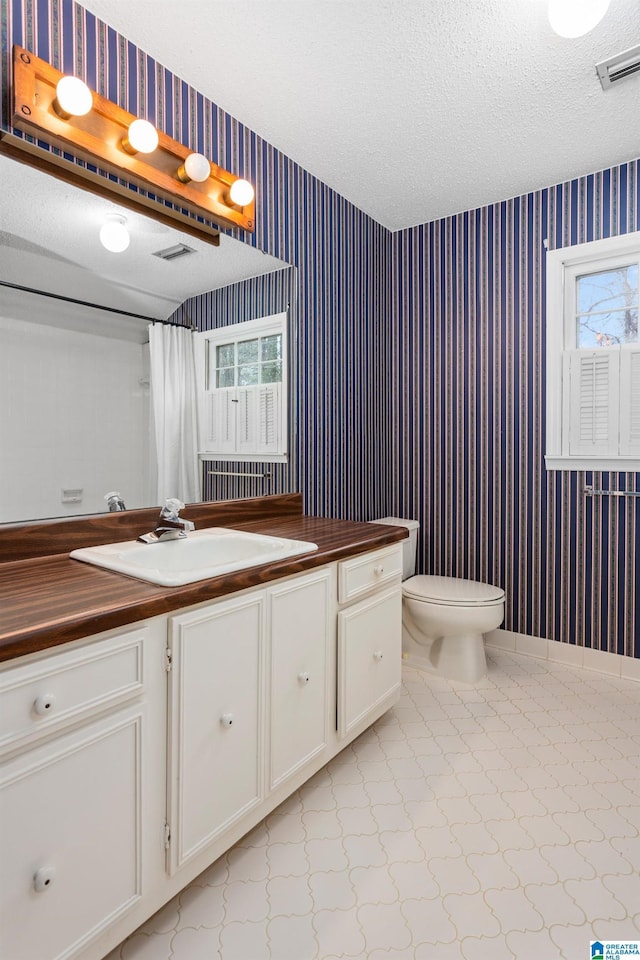 bathroom featuring vanity, toilet, a textured ceiling, and walk in shower