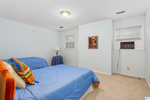 bedroom featuring light carpet and a textured ceiling