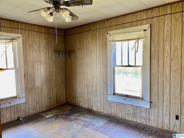 empty room with dark hardwood / wood-style flooring, a wealth of natural light, and ceiling fan