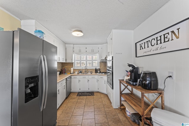 kitchen with sink, white cabinets, backsplash, stainless steel appliances, and a textured ceiling