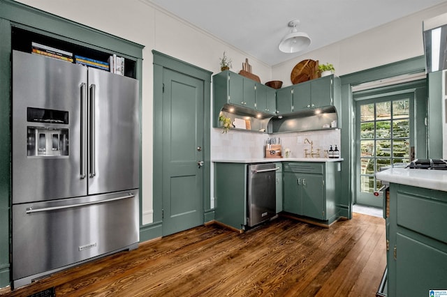 kitchen featuring dark wood-type flooring, green cabinetry, high end fridge, and backsplash