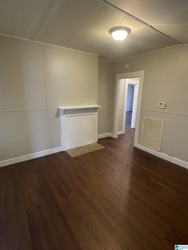 unfurnished room featuring dark wood-type flooring, visible vents, and baseboards