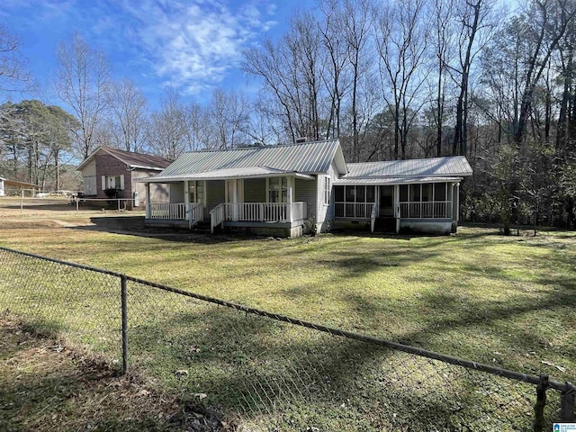 view of front of property with covered porch, a front yard, a sunroom, metal roof, and fence