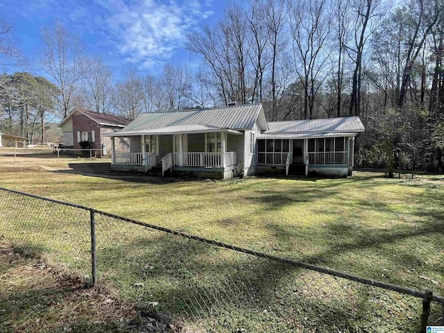 view of front of house with metal roof, a front lawn, fence, and a sunroom