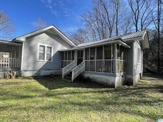 view of front of property featuring metal roof, crawl space, a front yard, and a sunroom