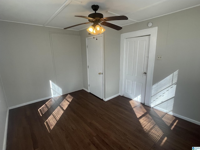 unfurnished bedroom with dark wood-type flooring, ceiling fan, and baseboards