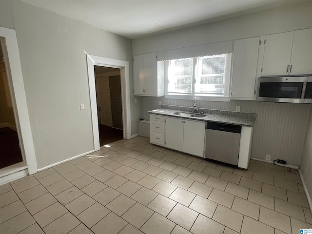 kitchen with stainless steel appliances, light countertops, white cabinets, a sink, and baseboards