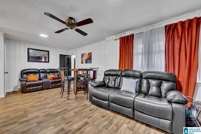 living room with ceiling fan, light hardwood / wood-style flooring, and a textured ceiling