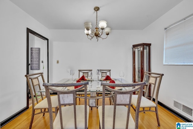 dining room with light hardwood / wood-style flooring and a notable chandelier