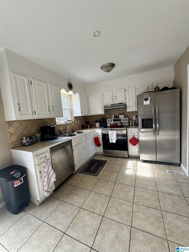 kitchen featuring sink, light tile patterned floors, stainless steel appliances, tasteful backsplash, and white cabinets