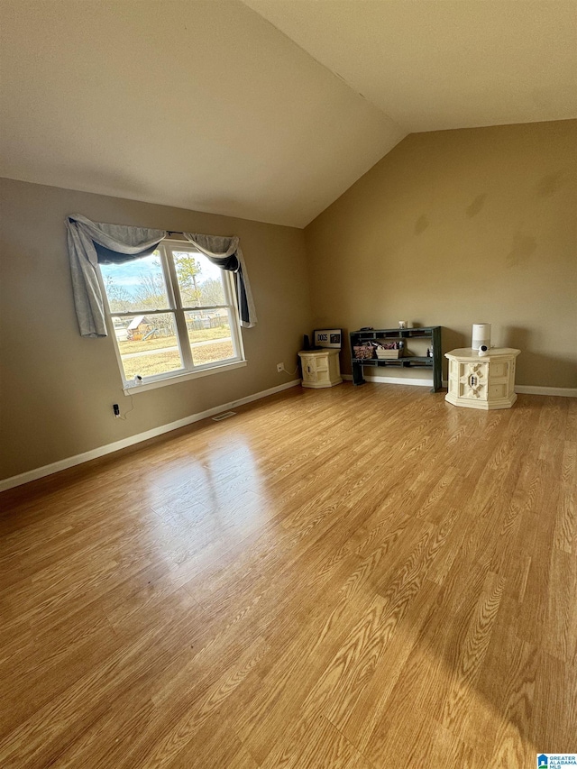 additional living space featuring lofted ceiling and light hardwood / wood-style floors