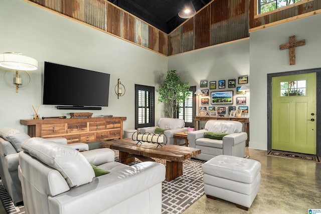 living room with a towering ceiling and concrete floors