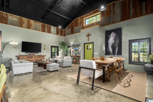 dining room featuring a healthy amount of sunlight, concrete floors, and high vaulted ceiling