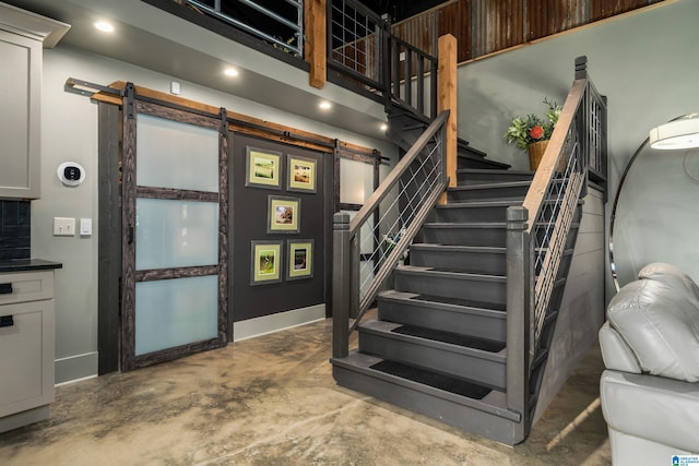 stairs featuring concrete flooring and a barn door