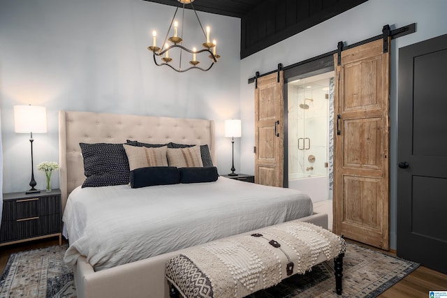 bedroom featuring ensuite bathroom, a barn door, a chandelier, and dark hardwood / wood-style flooring