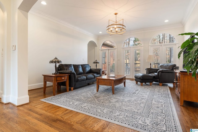 living room with french doors, ornamental molding, an inviting chandelier, and light hardwood / wood-style flooring