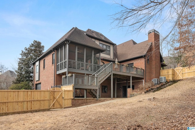 back of house featuring a wooden deck, a sunroom, and central air condition unit