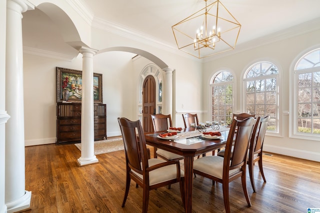 dining room featuring decorative columns, crown molding, and hardwood / wood-style flooring