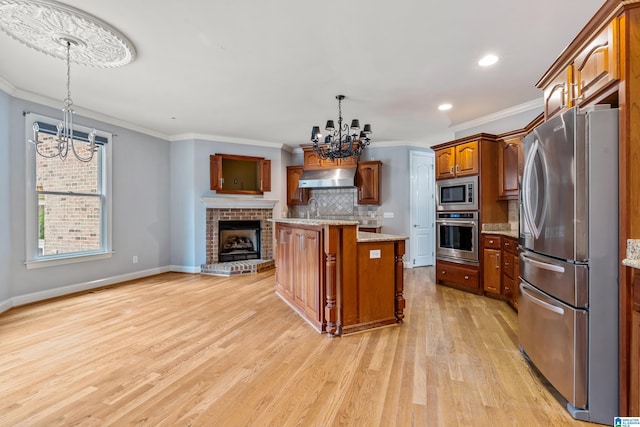 kitchen featuring stainless steel appliances, a center island, light stone counters, a notable chandelier, and decorative light fixtures